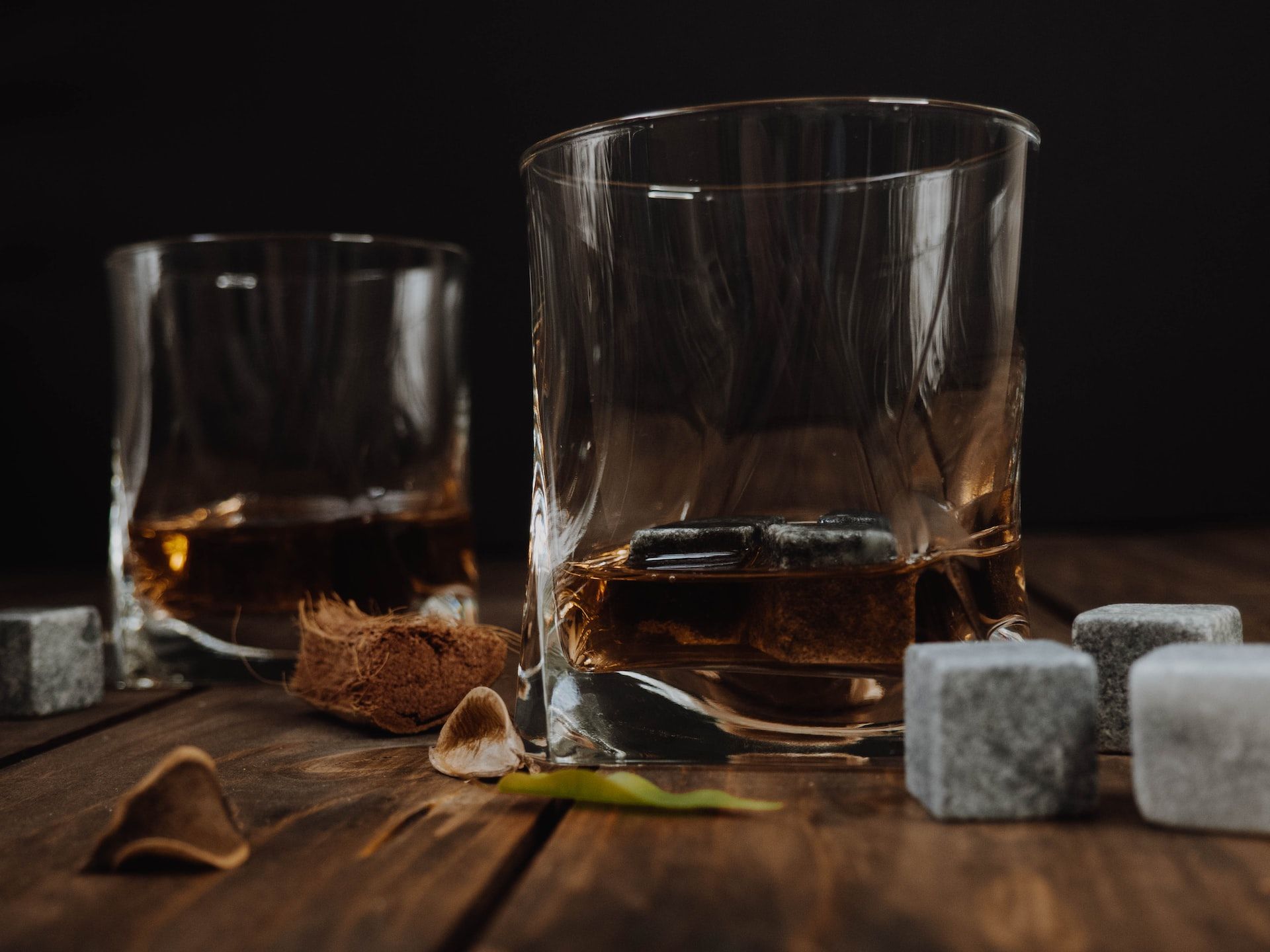 Two whiskey glasses on a wooden table.