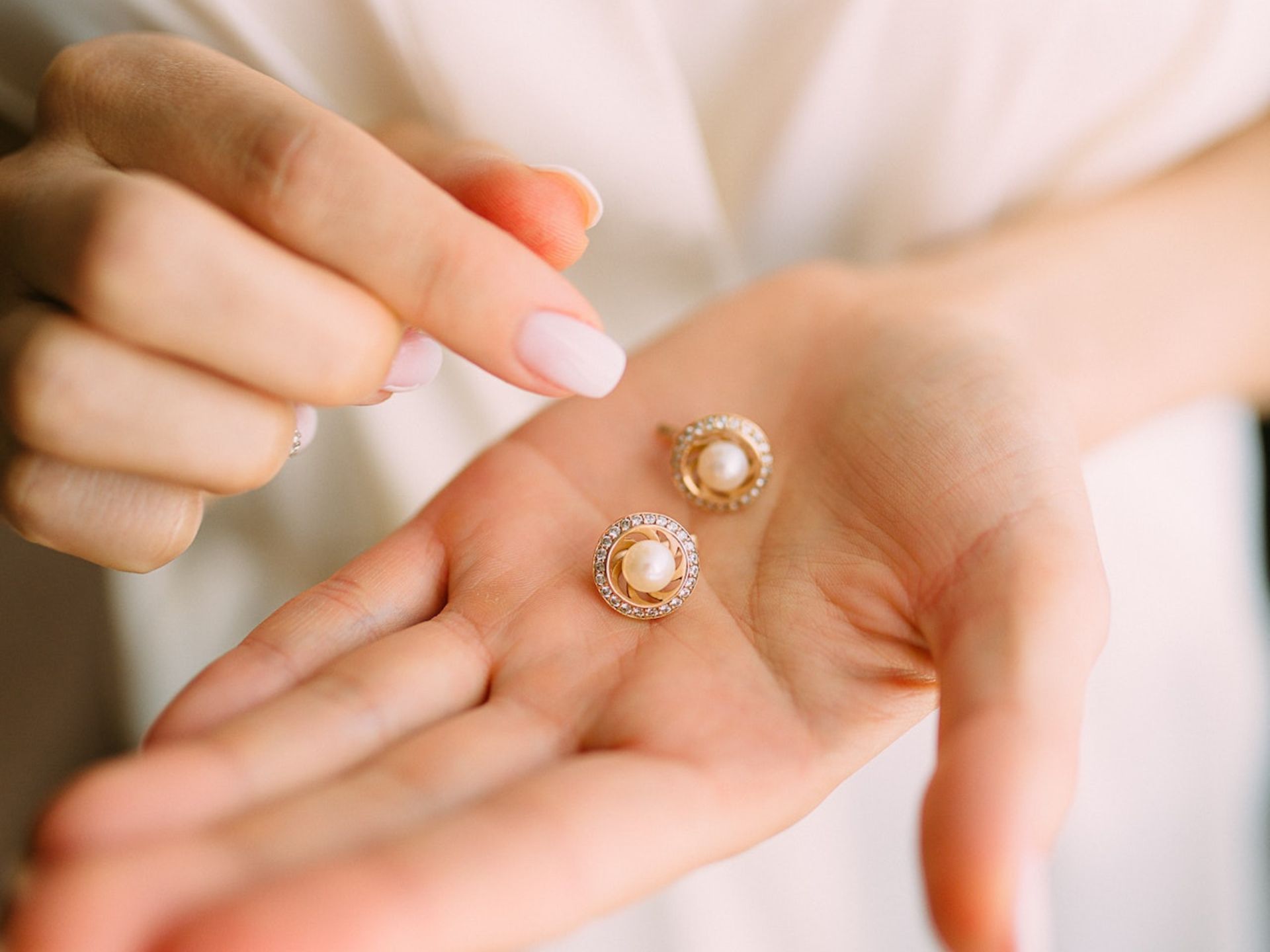 A bride holding pearl earrings.