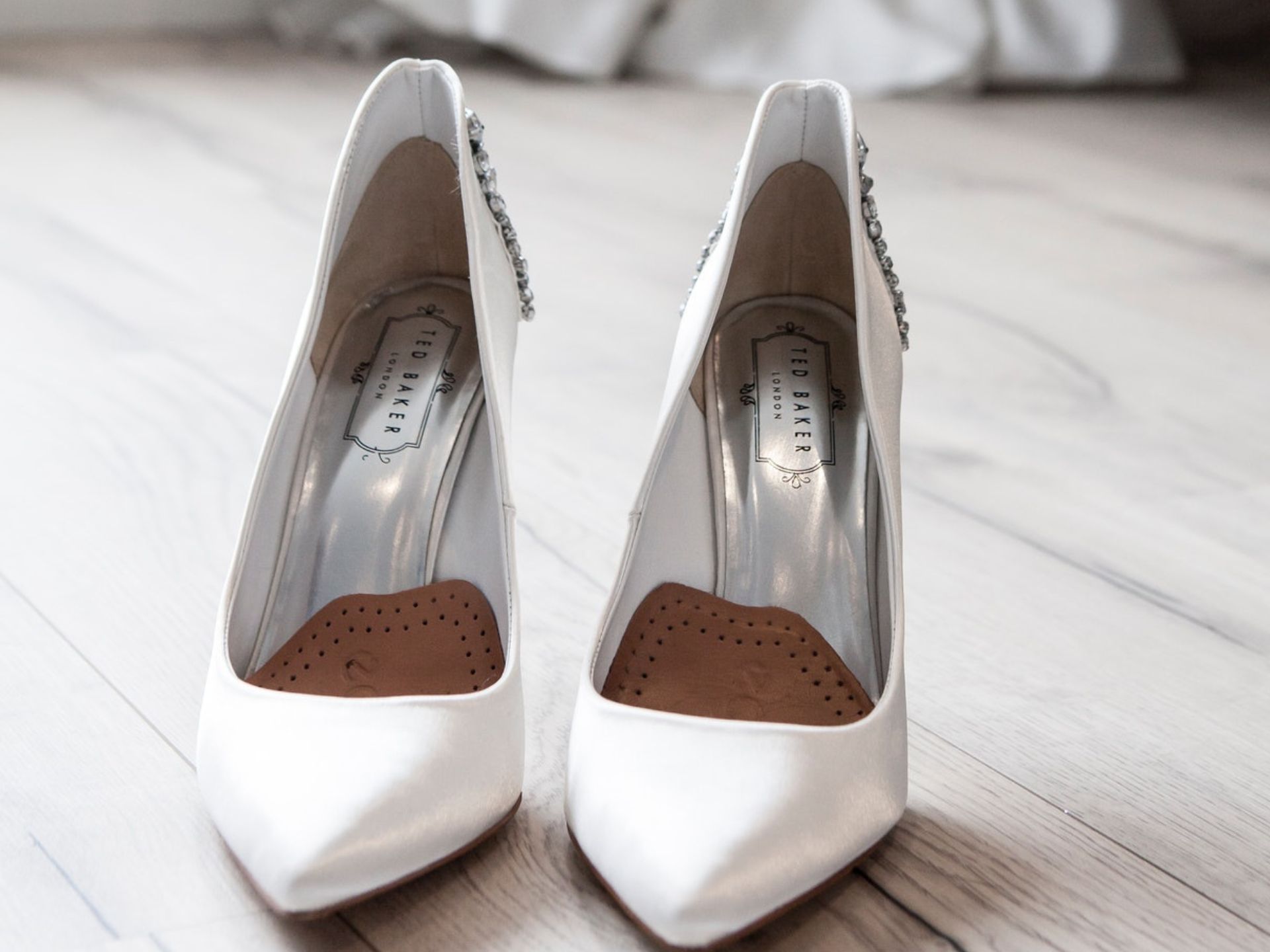 A bride's white heels on a wooden floor.