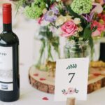 A wedding table with a pink and purple flower centerpiece.