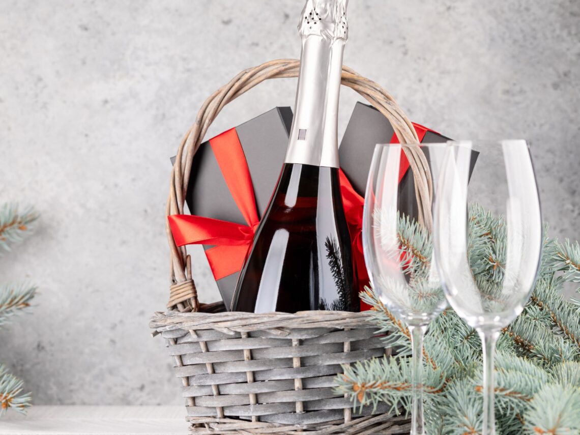 A wedding gift basket with red wine and wine glasses.