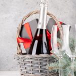 A wedding gift basket with red wine and wine glasses.