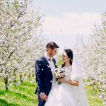 A bride and groom under cherry blossom trees at the spring wedding.