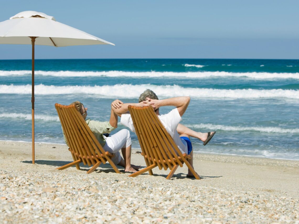 A couple sitting in chairs on the beach.
