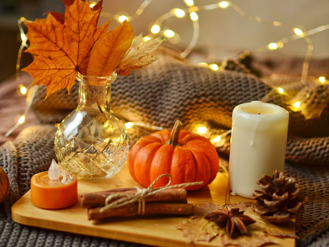 A table with warm lights and mini pumpkins.