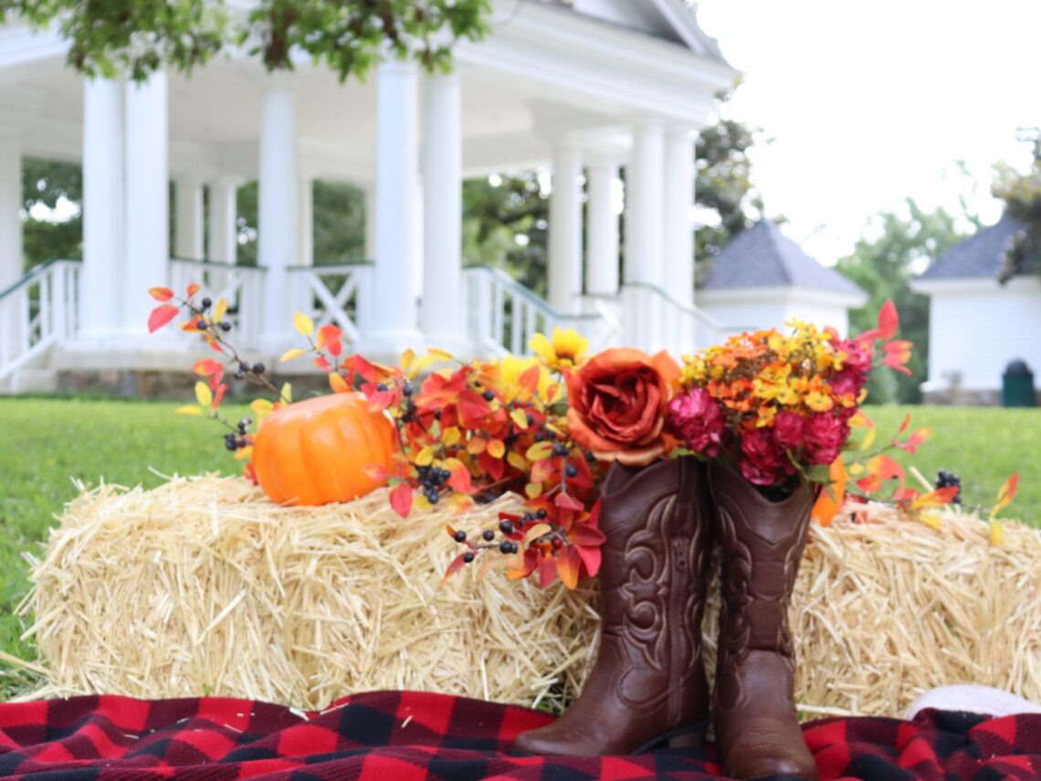 A hay bale that has mini orange pumpkins in an outdoor wedding.