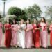 A group of bridesmaids wearing a mixture of red and light pink bridesmaid dresses.