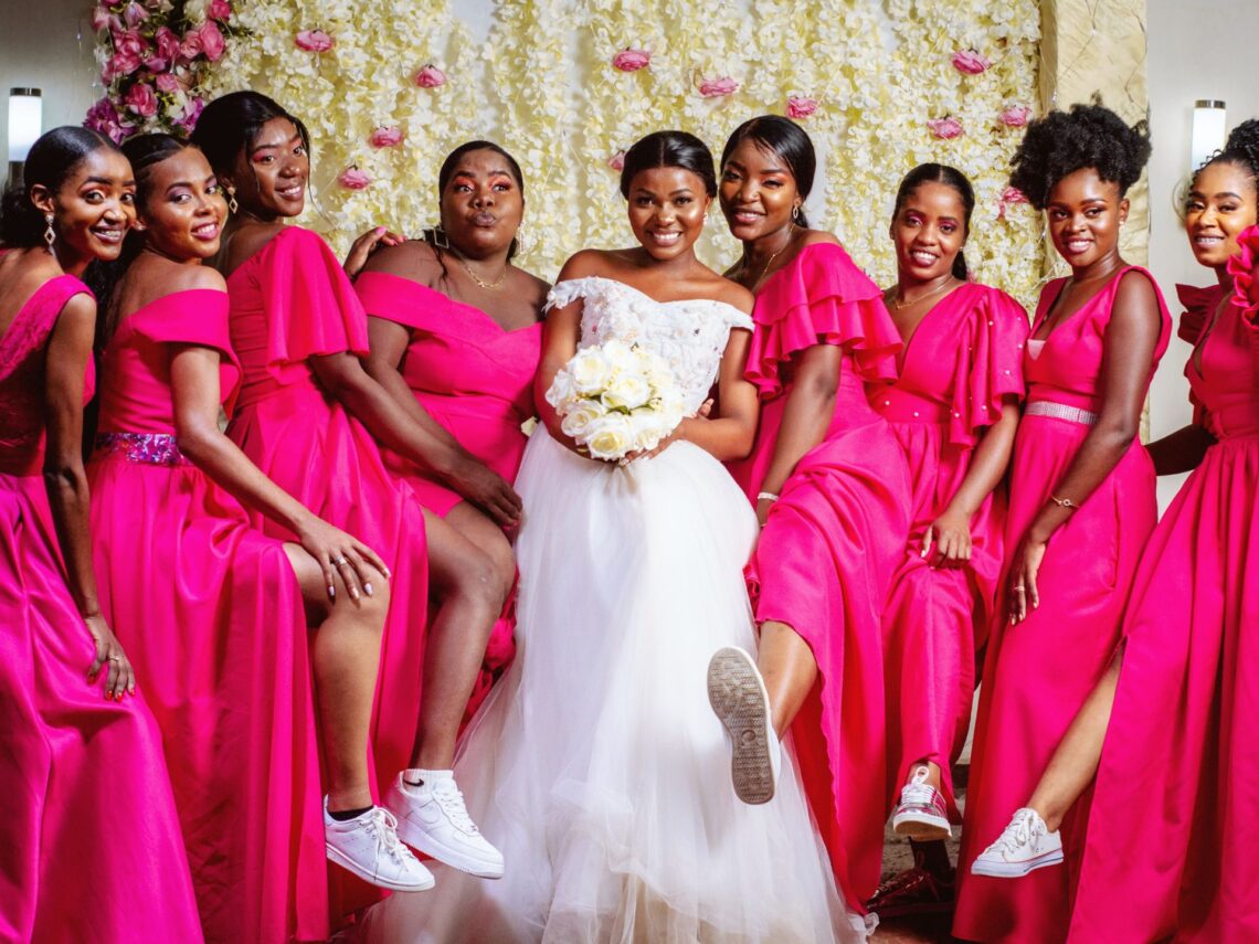 A group of bridesmaids wear fuchsia pink colored bridesmaids dresses.