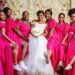 A group of bridesmaids wear fuchsia pink colored bridesmaids dresses.