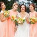 Bridesmaids wearing peach dresses and holding colorful flower bouquets.