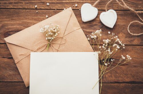 A wooden table with white rustic wedding invitations.