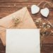 A wooden table with white rustic wedding invitations.