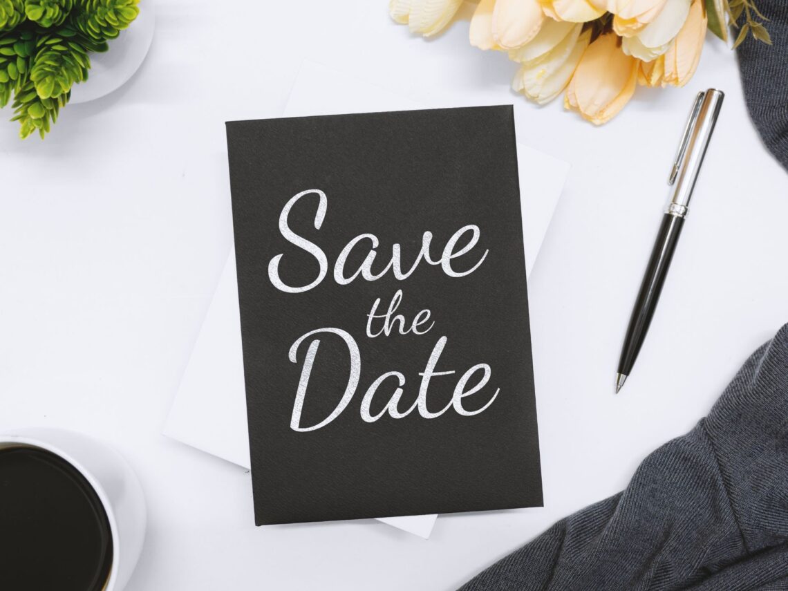 A table with a black and white colored save the date card on top.