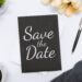 A table with a black and white colored save the date card on top.