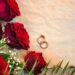 A table with red roses and gold wedding rings.