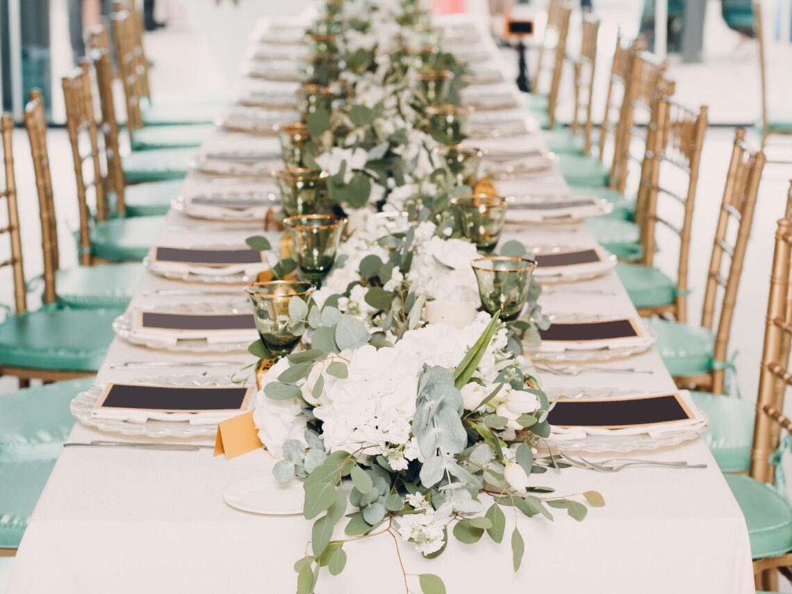 A wedding table with sage green decor on top.