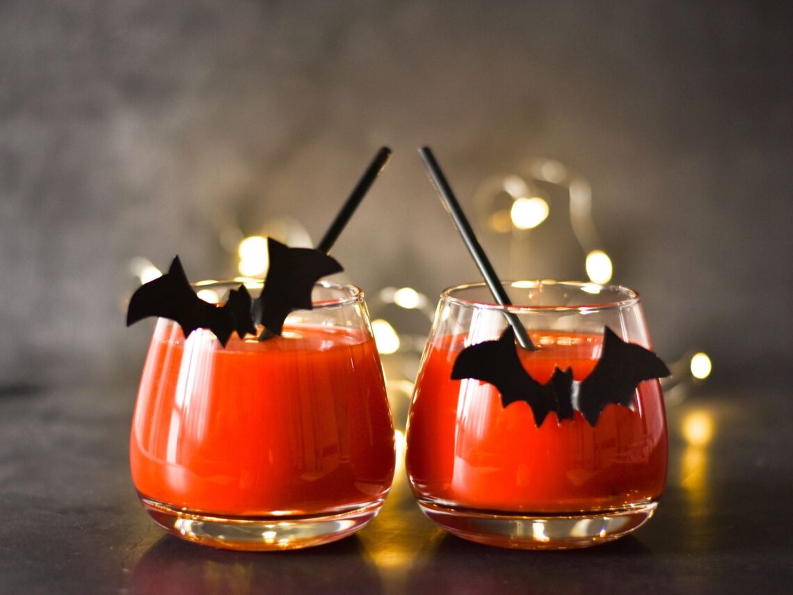 Two orange Halloween themed cocktails on a table.