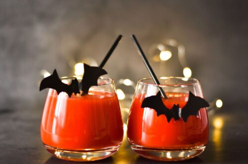 Two orange Halloween themed cocktails on a table.