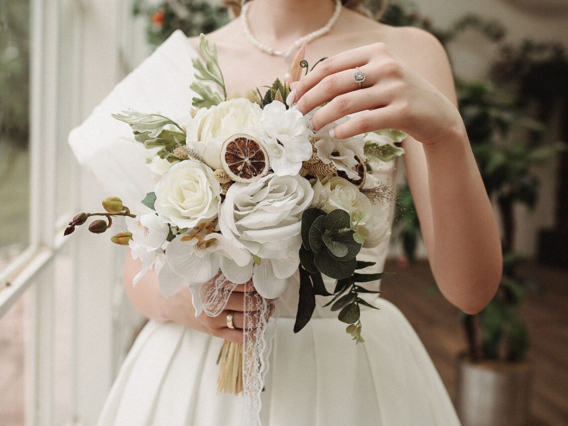 A bride holding a neutral colored wedding bouquet.