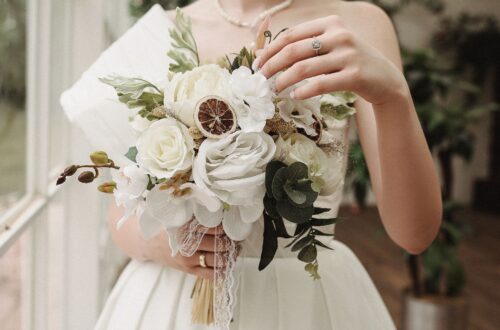 A bride holding a neutral colored wedding bouquet.