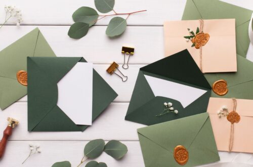 A table with sage green colored wedding invitations.