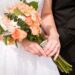 A bride carrying a peach colored wedding bouquet.