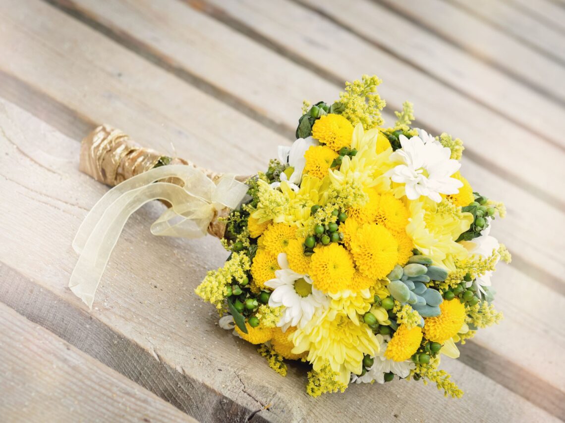 A yellow wedding bouquet on a wooden table.