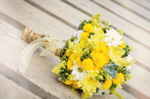 A yellow wedding bouquet on a wooden table.