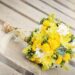 A yellow wedding bouquet on a wooden table.