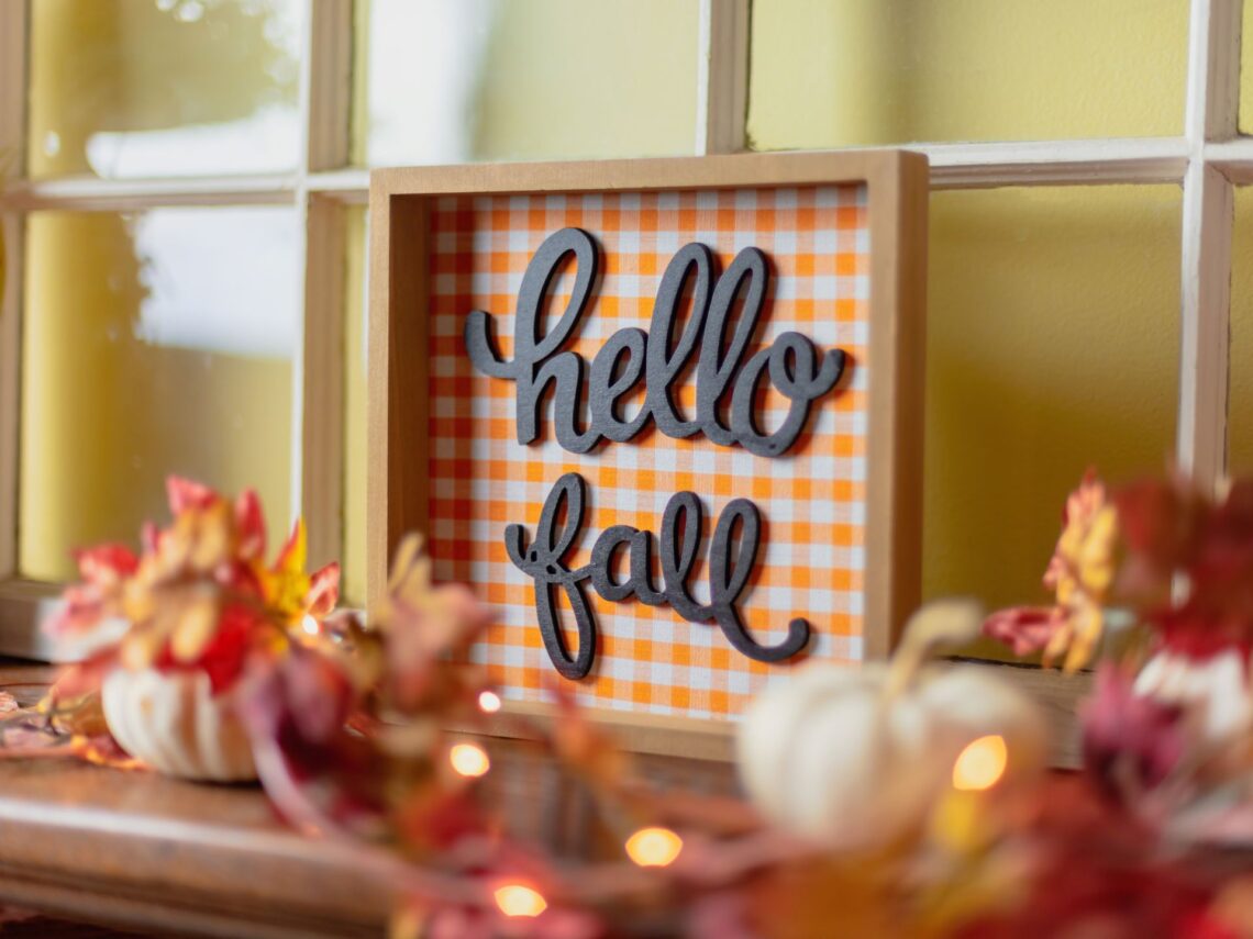 A table with fall leaves, pumpkins, and home decor signs.