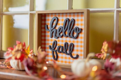 A table with fall leaves, pumpkins, and home decor signs.