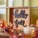 A table with fall leaves, pumpkins, and home decor signs.