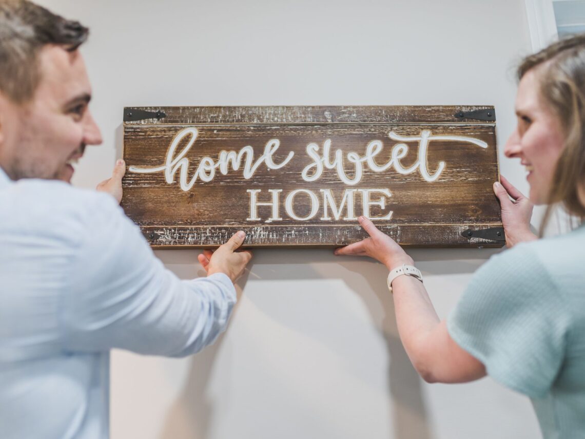 A couple putting up a home sweet home sign.