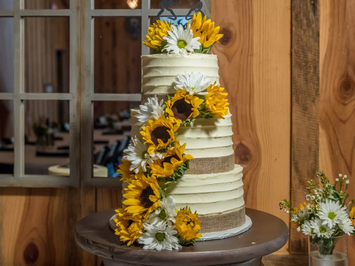 A rustic wedding cake decorated with sunflowers.