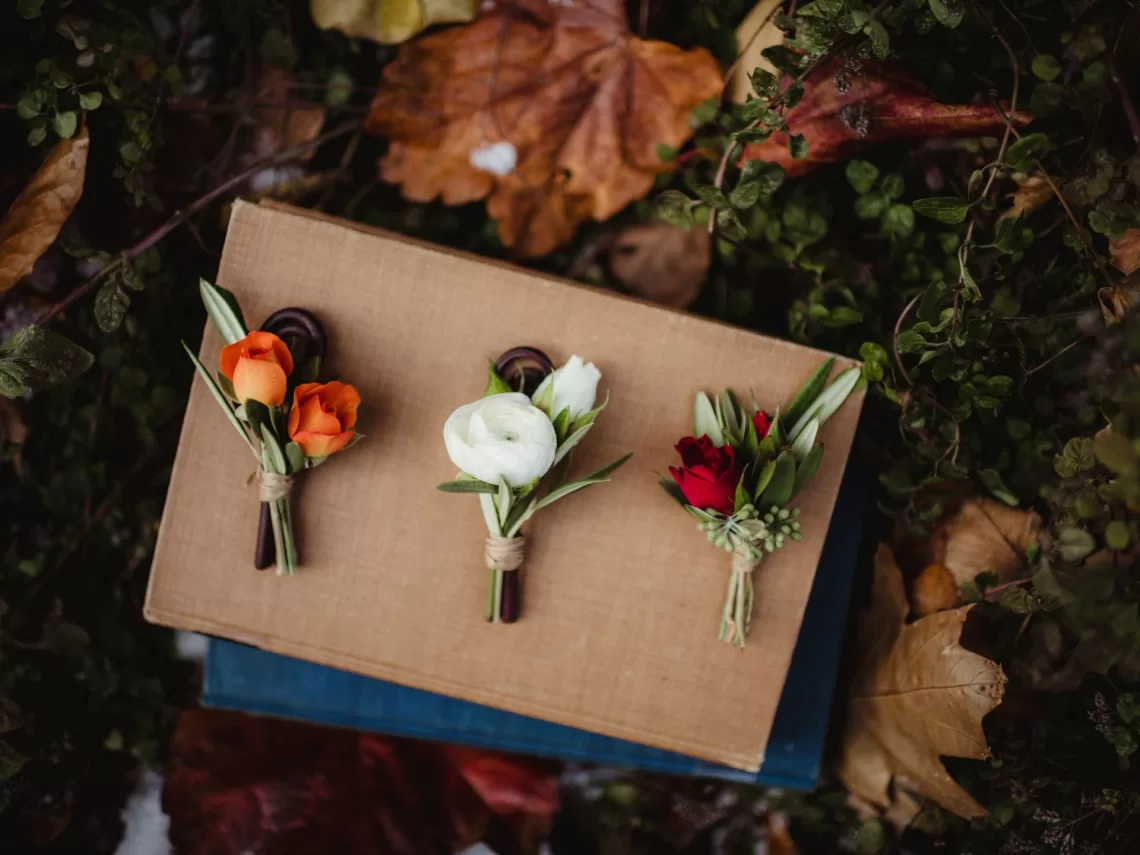 A table with fall leaves and 2 rustic fall wedding boutonnieres.